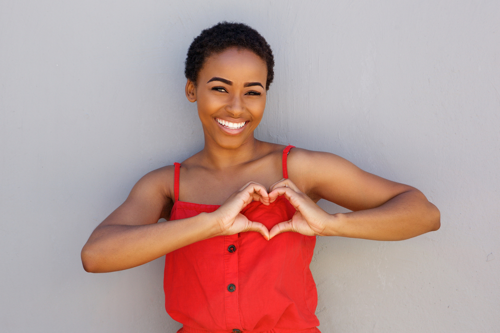 young woman with heart shape hand sign