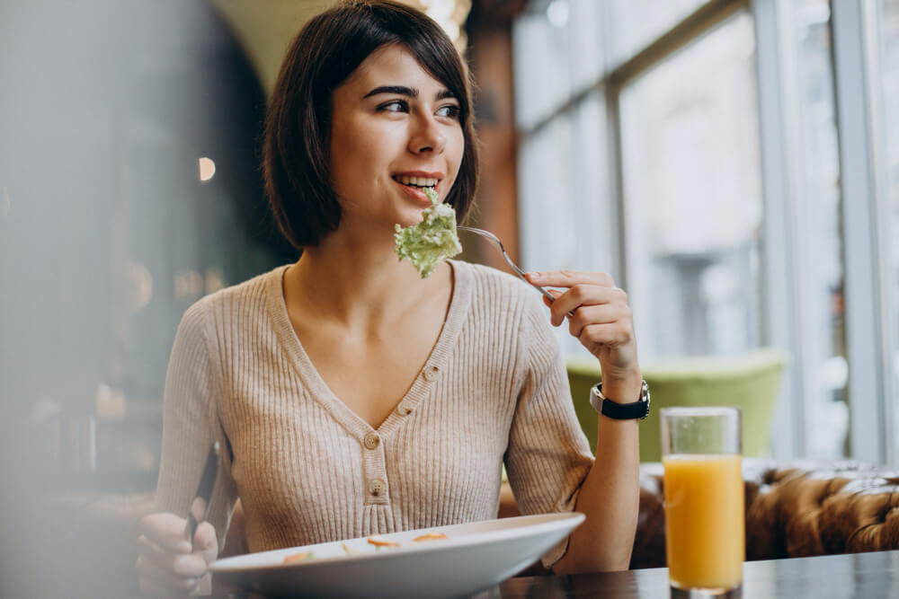 Young woman eating healthy breakfast with juice in a cafe