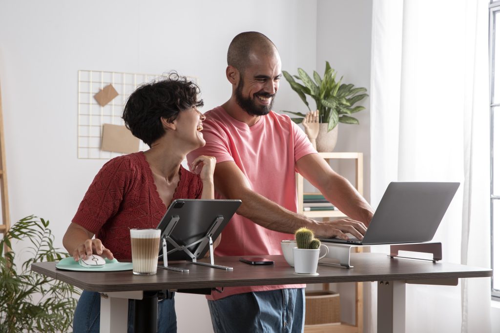 Happy couple working from home using laptops and ergonomic workstation.
