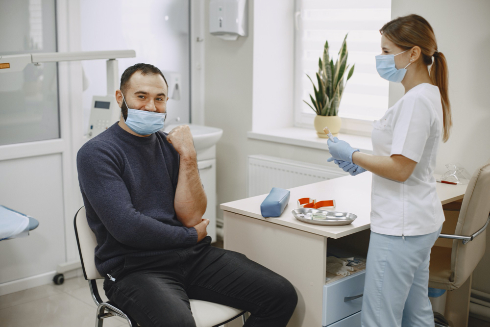 Skillful nurse is doing blood test for man in clinic. man in a medical mask.