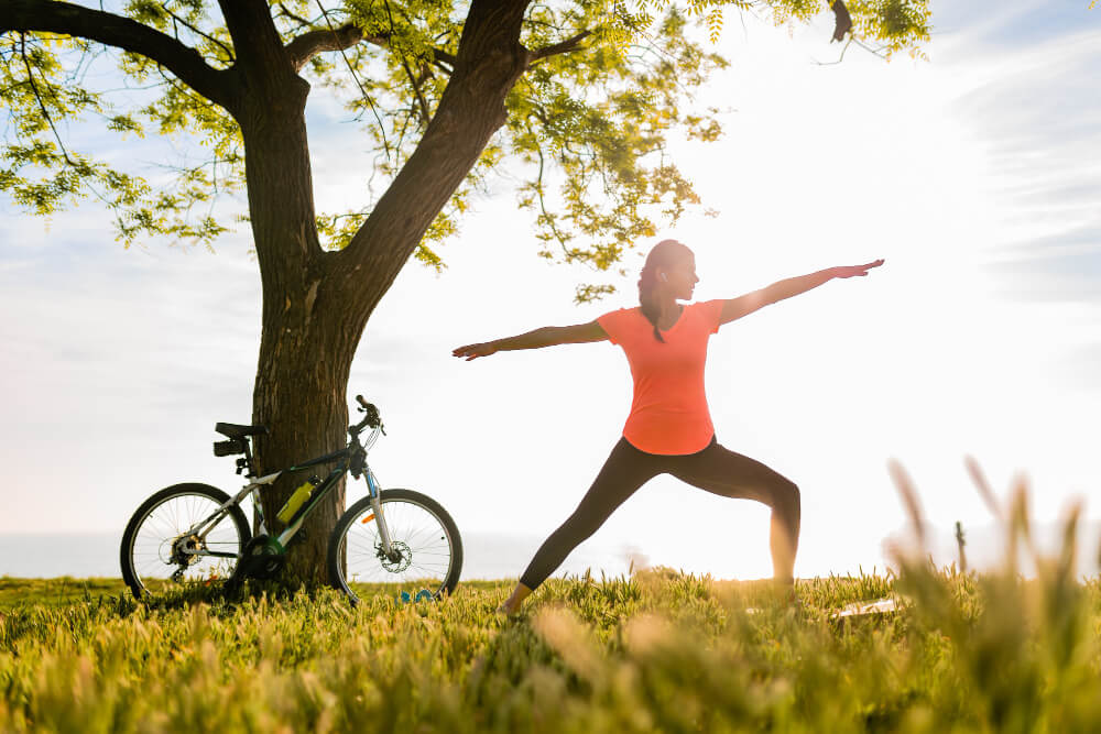 Slim beautiful woman silhouette doing sports in morning in park doing yoga
