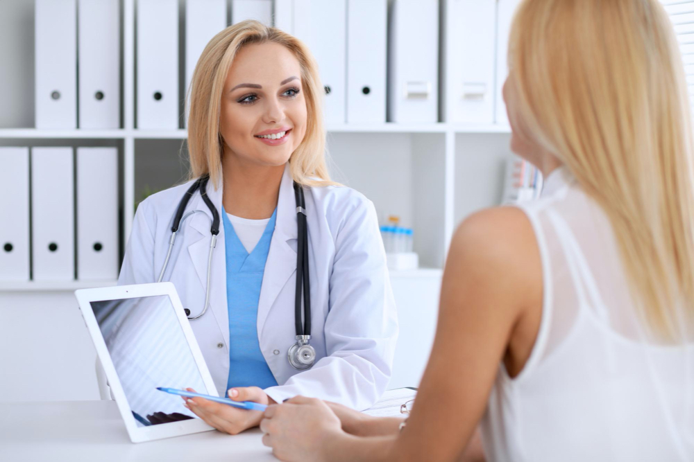 doctor and patient discussing something while phisician pointing into laptop computer. 