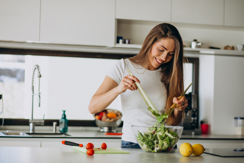 young woman making salad at the kitchen