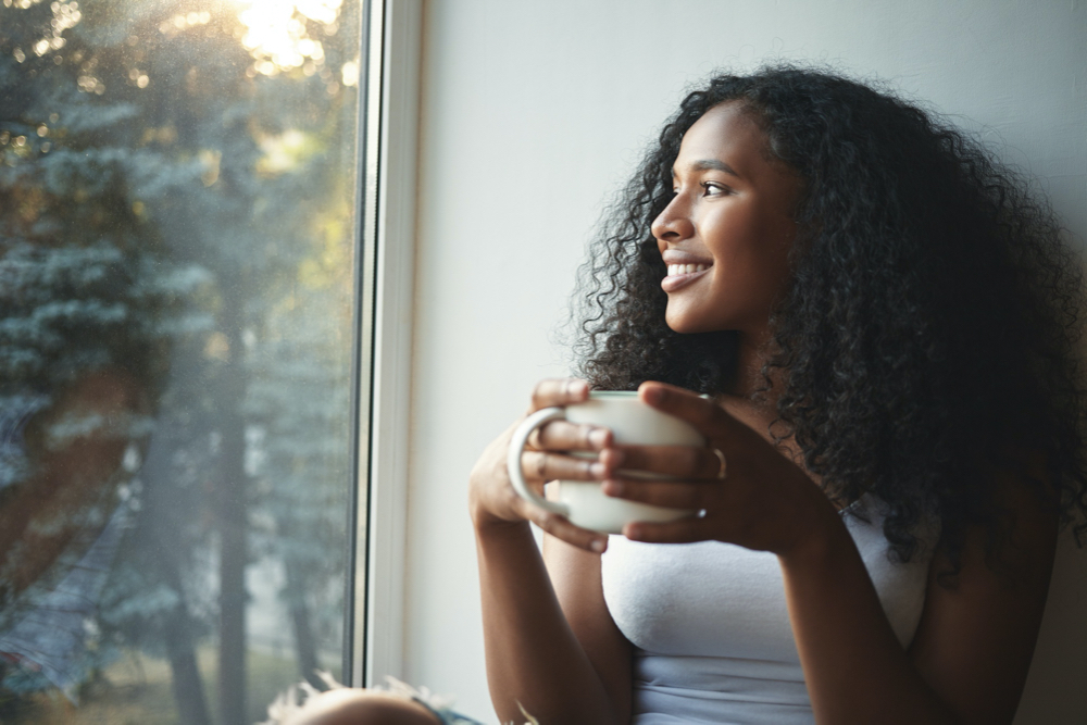 Free photo morning routine. portrait of happy charming young mixed race female with wavy hair enjoying summer view 
