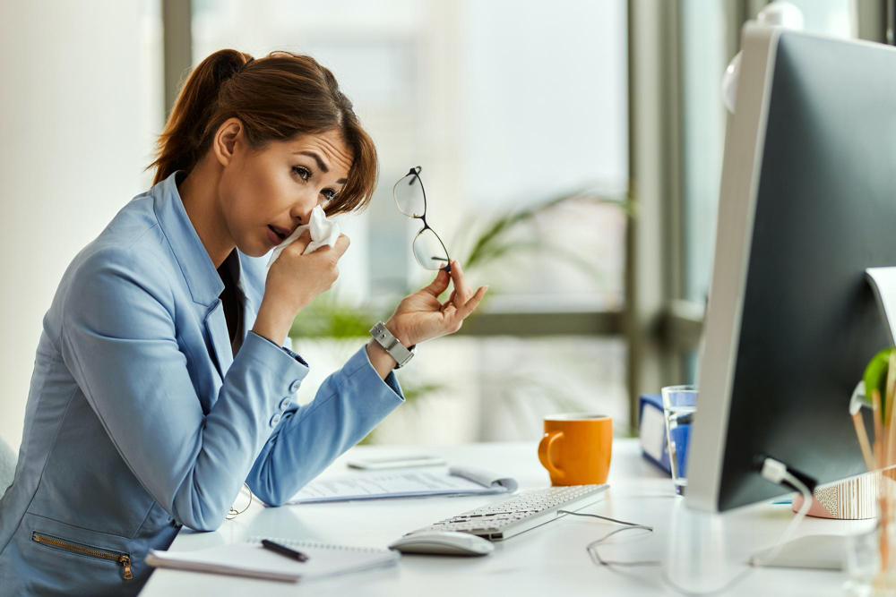 photo young businesswoman having an allergy and using facial tissue while working on a computer in the office