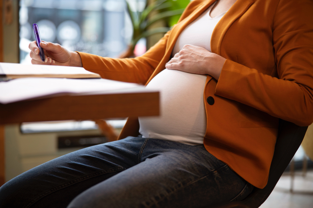 pregnant woman at work writing on journal