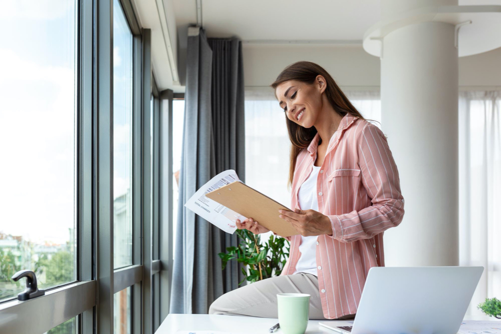 attractive young woman reading through papers at her apartment