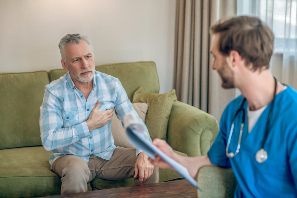 photo upset gray-haired man in a plaid shirt complaining of his chest pain to a cardiologist