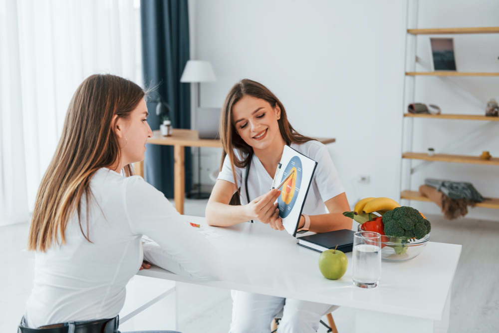 woman showing illustration to the female customer professional medical worker in white coat is in the office