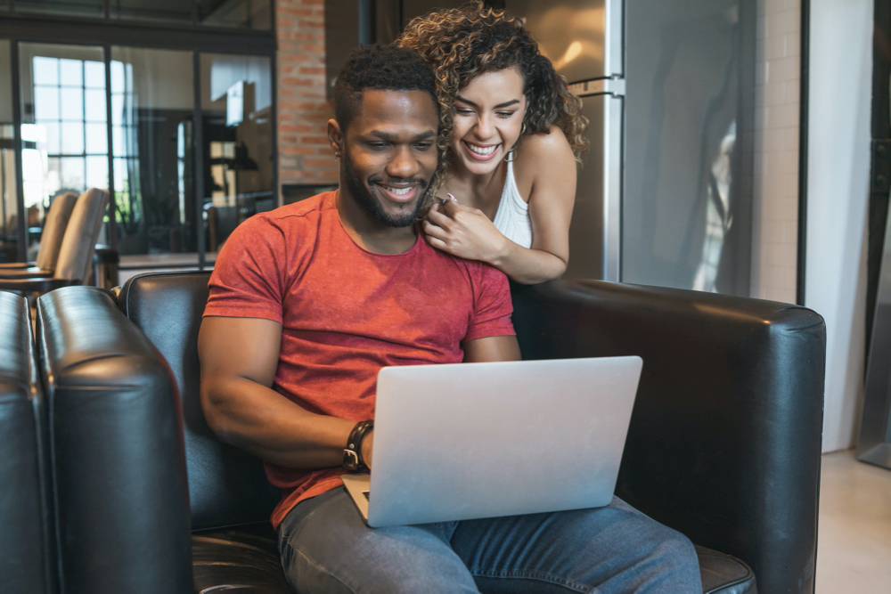 young couple spending time together while using a laptop at home.