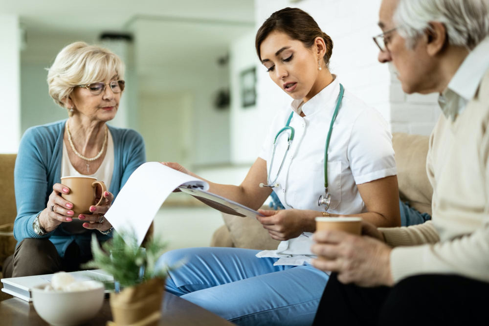 Free photo young healthcare worker and senior couple analyzing medical test results during home visit
