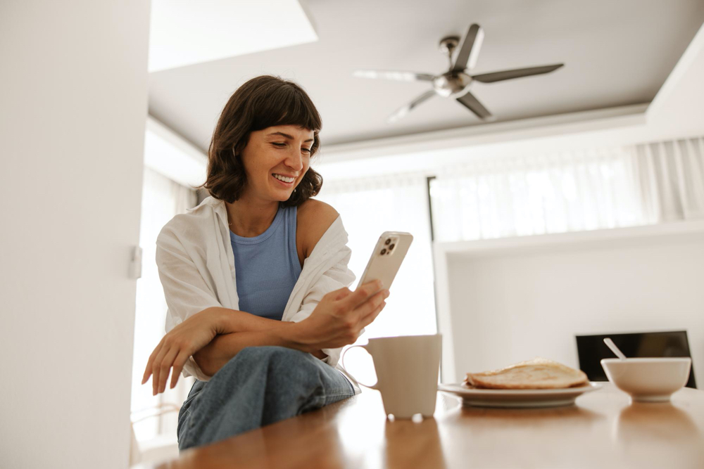 close up view of woman sitting at kitchen smiling at phone