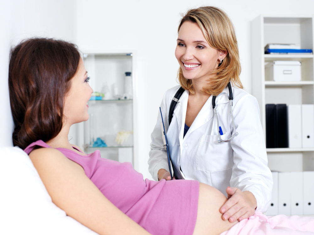 photo happy doctor caring about young pregnant woman in hospital
