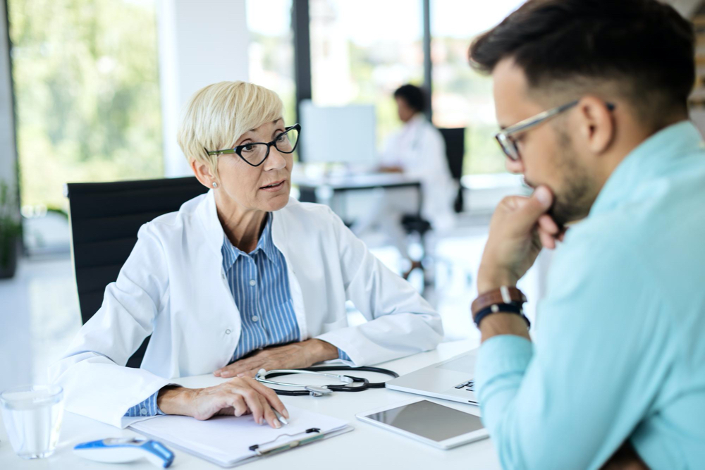 photo mature doctor communicating with her patient while analyzing his medical data at the clinic