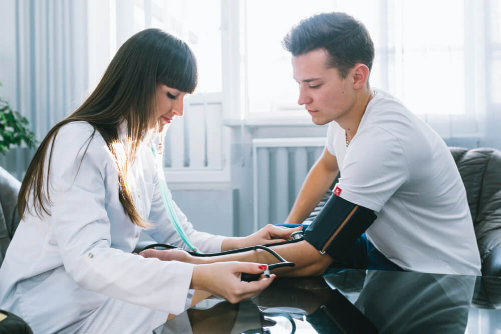 Woman measuring pressure and pulse to patient