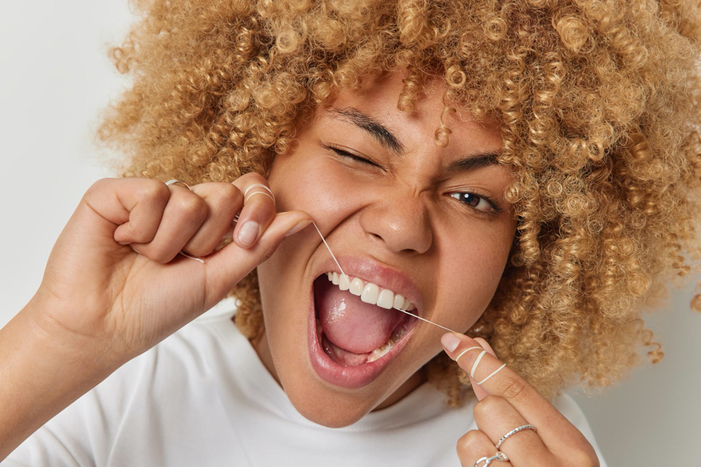 beautiful woman flossing to soothe her teeth and gum swelling