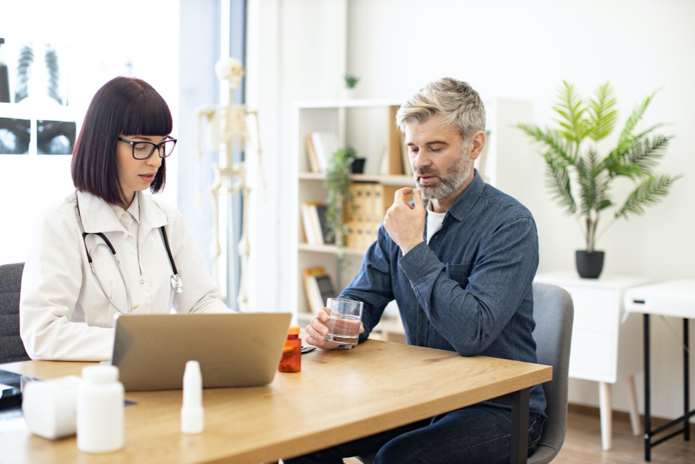 patient taking pills while doctor making medical records