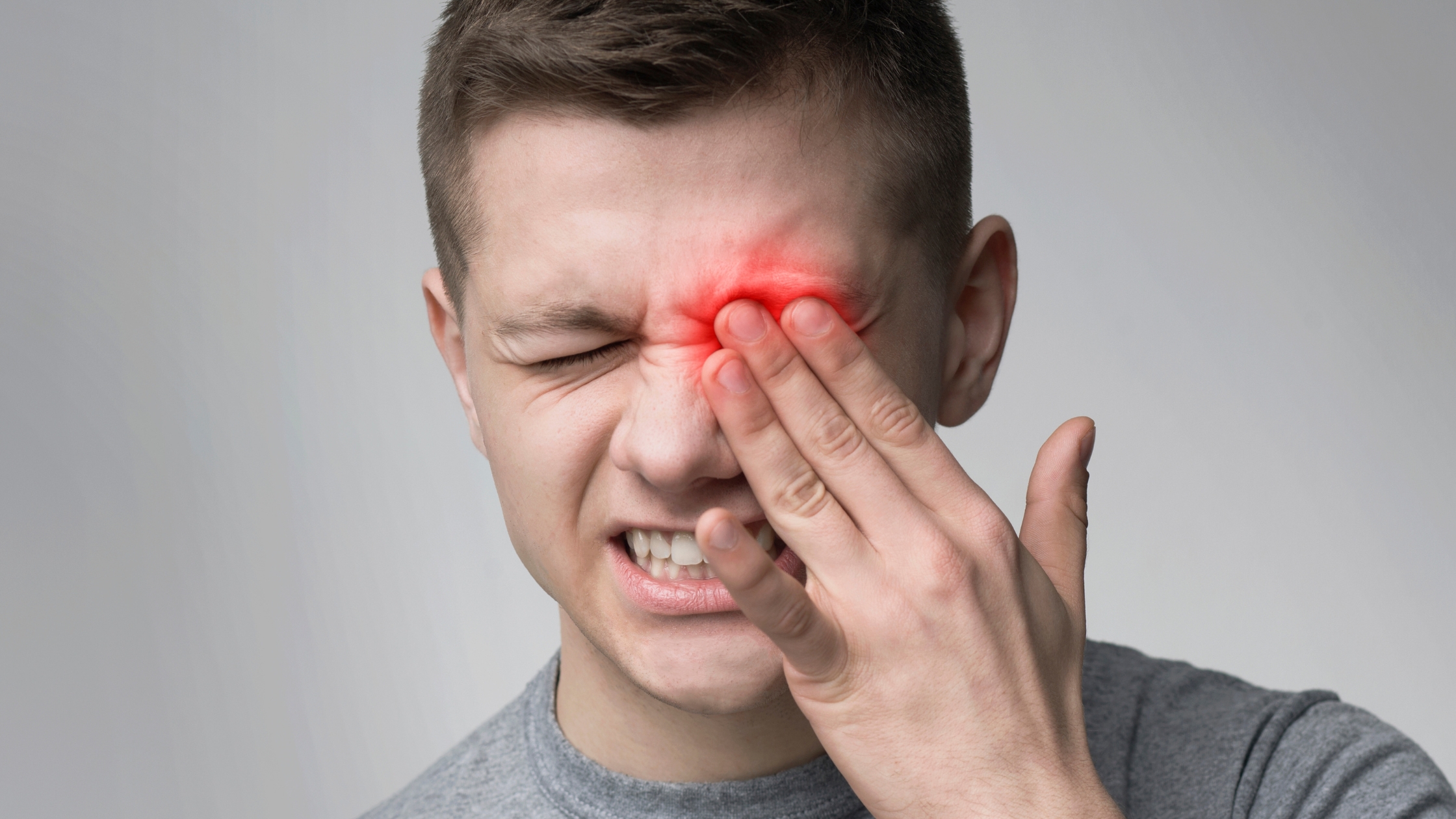 A man with periorbital cellulitis touching his infected eye