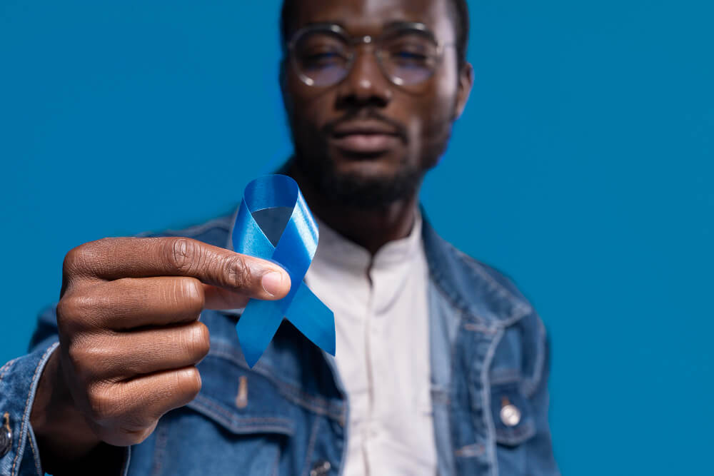 African american man holding a blue ribbon for colorectal cancer awareness