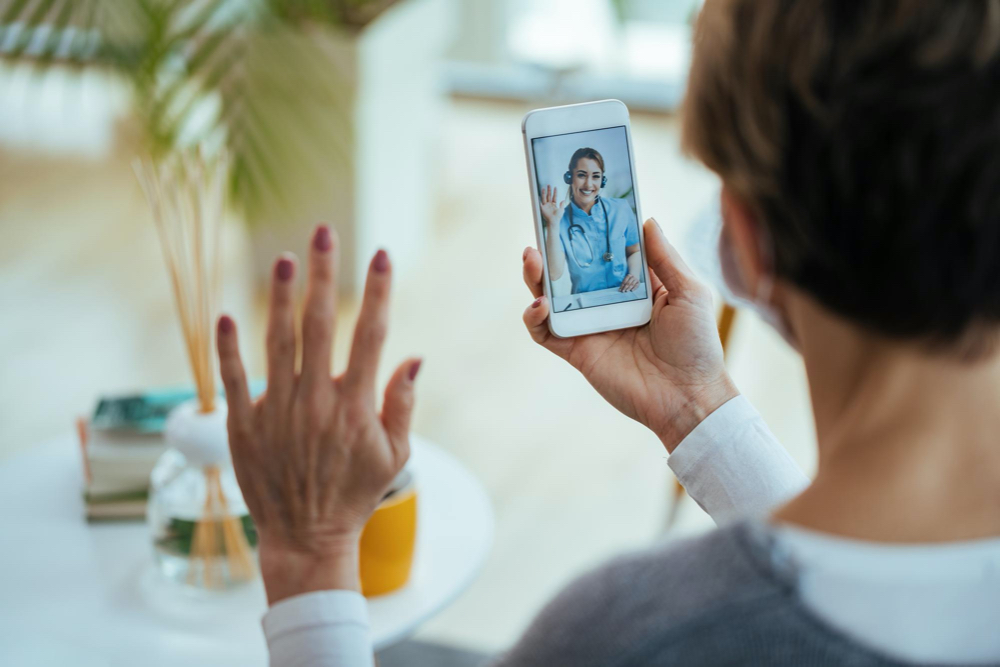 closeup of woman greeting her doctor while using smart phone and having video call focus