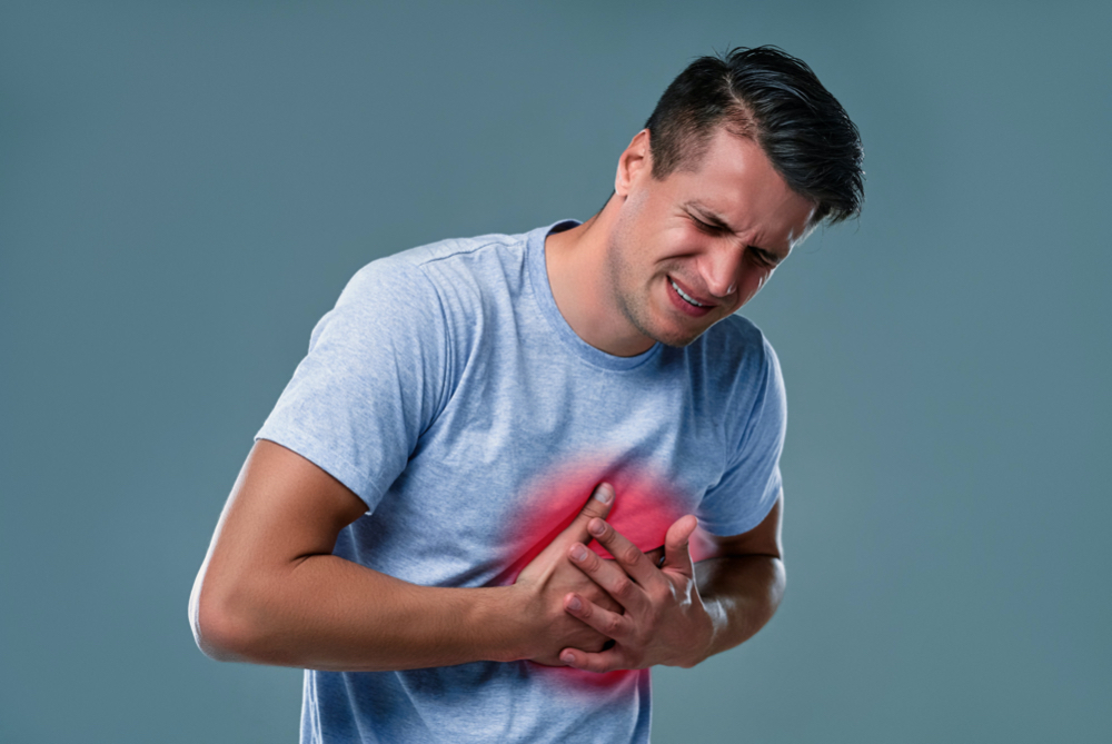 man in white t-shirt with heart pain on gray room