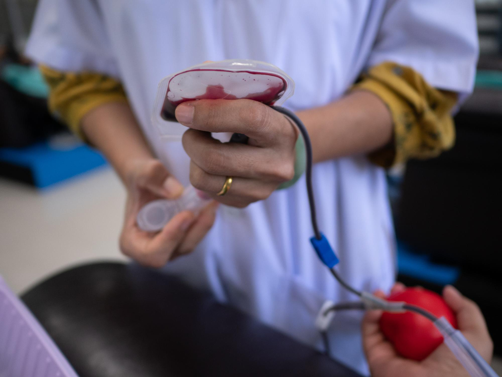 Close-up of doctor holding bag while standing by patient during blood donation