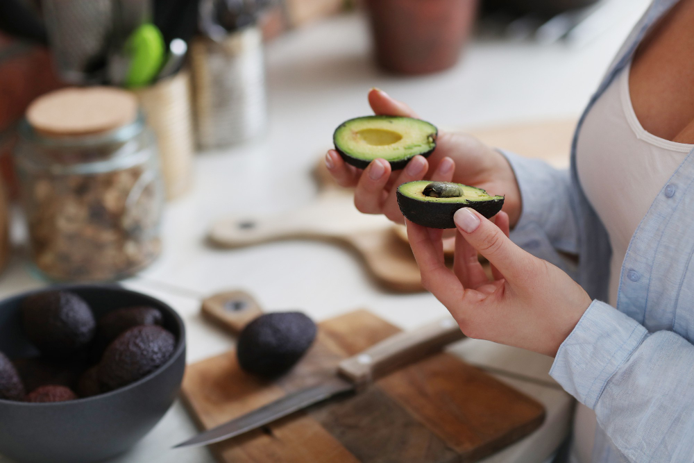 woman in kitchen cutting healthy fat avocado