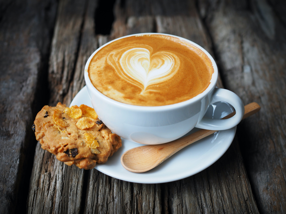 Fresh coffee steams on wooden table close up