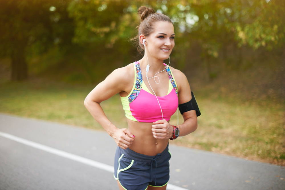 Young woman exercising outdoor. Summer helps in getting motivation